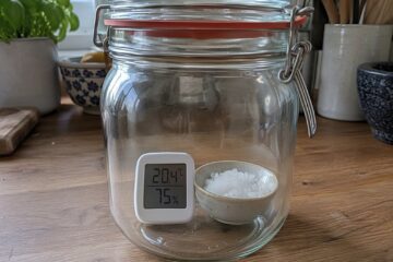 Digitales Hygrometer in einem verschlossenen Einmachglas neben einer Schale mit feuchtem Salz